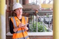 A concerned female civil engineer inspects and supervises a construction site building with scaffolding, wears a hard hat