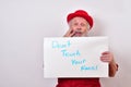 Concerned gentleman is touching his face while holding a sign tha says DON`T TOUCH YOUR FACE