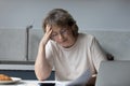 Concerned middle aged homeowner woman reading paper at laptop