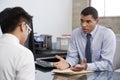 Concerned mixed race male therapist counselling male patient Royalty Free Stock Photo