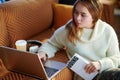 Concerned modern teen girl with laptop and book learning coding