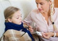 Concerned mother giving pills to daughter with fever Royalty Free Stock Photo