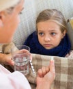 Concerned mother giving pills to daughter with fever Royalty Free Stock Photo