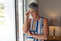 Concerned senior caucasian woman standing looking out of window holding cup of coffee Royalty Free Stock Photo