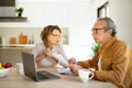 Concerned senior spouses sitting at desk in front of laptop, checking bills, working on family budget, kitchen interior Royalty Free Stock Photo