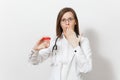 Concerned upset young doctor woman with stethoscope isolated on white background. Female doctor in medical gown holds Royalty Free Stock Photo