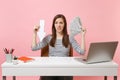 Concerned woman holding down value fall arrow, bundle lots of dollars, cash money work at white desk with pc laptop Royalty Free Stock Photo