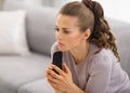 Concerned woman sitting on sofa and holding mobile phone in hands Royalty Free Stock Photo