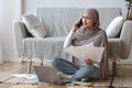 Concerned woman working with papers and talking on cellphone at home Royalty Free Stock Photo