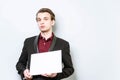 Concerned young european business man in red polo shirt and blazer holding blank A4 signboard. Business background with copy space Royalty Free Stock Photo