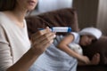 Concerned young mother sit by sick child bed hold thermometer Royalty Free Stock Photo