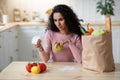 Concerned Young Woman Checking Bills In Kitchen After Grocery Shopping Royalty Free Stock Photo