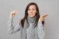 Concerned young woman in gray sweater, scarf spreading hands holding medication tablet, aspirin pill isolated on grey