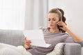 Concerned young woman with letter and talking cell phone