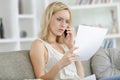 Concerned young woman with letter and talking cell phone Royalty Free Stock Photo