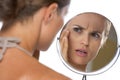 Concerned young woman looking in mirror