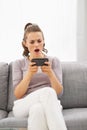 Concerned young woman sitting on sofa and reading sms Royalty Free Stock Photo