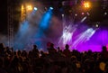 Concert crowd attending a concert, people silhouettes are visible, backlit by stage lights. Raised hands and smart phones are visi Royalty Free Stock Photo