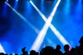 Concert crowd attending a concert, people silhouettes are visible, backlit by stage lights. Raised hands and smart phones are visi Royalty Free Stock Photo