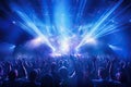 Concert crowd in front of bright stage lights at a music festival, night club under blue rays beam and young people holding light Royalty Free Stock Photo