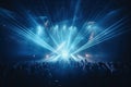 Concert crowd in front of a bright stage with lights and smoke, night club under blue rays beam and young people holding light Royalty Free Stock Photo
