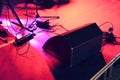 Concert stage under a red light with a lot of wires, mic stands and a big speaker on the floor Royalty Free Stock Photo