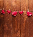 Concert for Valentine`s Day. Red hearts made of felt pinned with clothespins to a string against background of boards