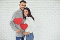 Concert Valentine`s Day. Young couple with hearts in hands on a white brick background