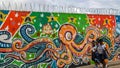 Concertina wire atop colorful mural serves as backdrop to school girls in Cap Haitien.