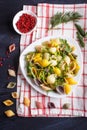 Conchiglie colored pasta with fresh greengrocery on a linen tablecloth on black wooden background