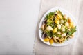 Conchiglie colored pasta with fresh greengrocery on a linen tablecloth on white wooden background