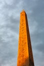 Concorde Obelisk in orange light from sunset against cloudy sky