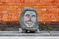 Concrete artifact along the city street with a brick wall background.