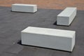 Concrete white park bench block shape on dark paving square, clean cast concrete surface gray brown white light barrier against