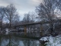 Concrete bridge over river in winter, snow covered riverbanks and trees Royalty Free Stock Photo