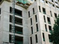 Concrete building high ceiling high-rise apartment condo tower skyscraper under construction with crane, scaffolding, safety nets Royalty Free Stock Photo