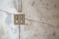 Concrete cement wall was cracked in the house where no people to live. Wall damage under light switch. White cement construction Royalty Free Stock Photo