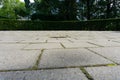 Concrete cobblestone paved courtyard surrounded by tall trees and shady curving hedge