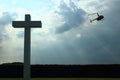 Concrete cross with clouded sky and helicopter