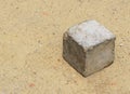 Concrete cube lying on sand ground used by poor kids to play as toy with space for message or object or logo