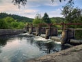 a concrete dam blocks a small river, the floodgates are open, the water flows freely