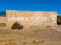 concrete fence with large inscription translating from Kyrgyz car washing prohibited, fine 500 som