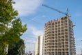 Concrete frame of tall apartment building under construction and tower crane in a city Royalty Free Stock Photo