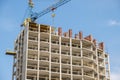 Concrete frame of tall apartment building under construction and tower crane in a city Royalty Free Stock Photo