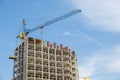 Concrete frame of tall apartment building under construction and tower crane in a city