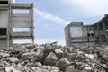 Concrete gray debris close-up on the background of the remains of the destroyed building against the sky. Background