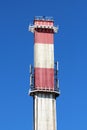 Concrete high red and white industrial chimney with two metal safety platforms and multiple cell phone transmitters Royalty Free Stock Photo