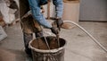 Concrete industry - young man worker adding water in the bucket full of cement