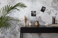 Concrete interior of home office with desk, image, lamp and office accessories. Grey concrete wall. Home decor. Template