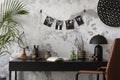 Concrete interior of home office with desk, image, lamp and office accessories. Grey concrete wall. Home decor. Template